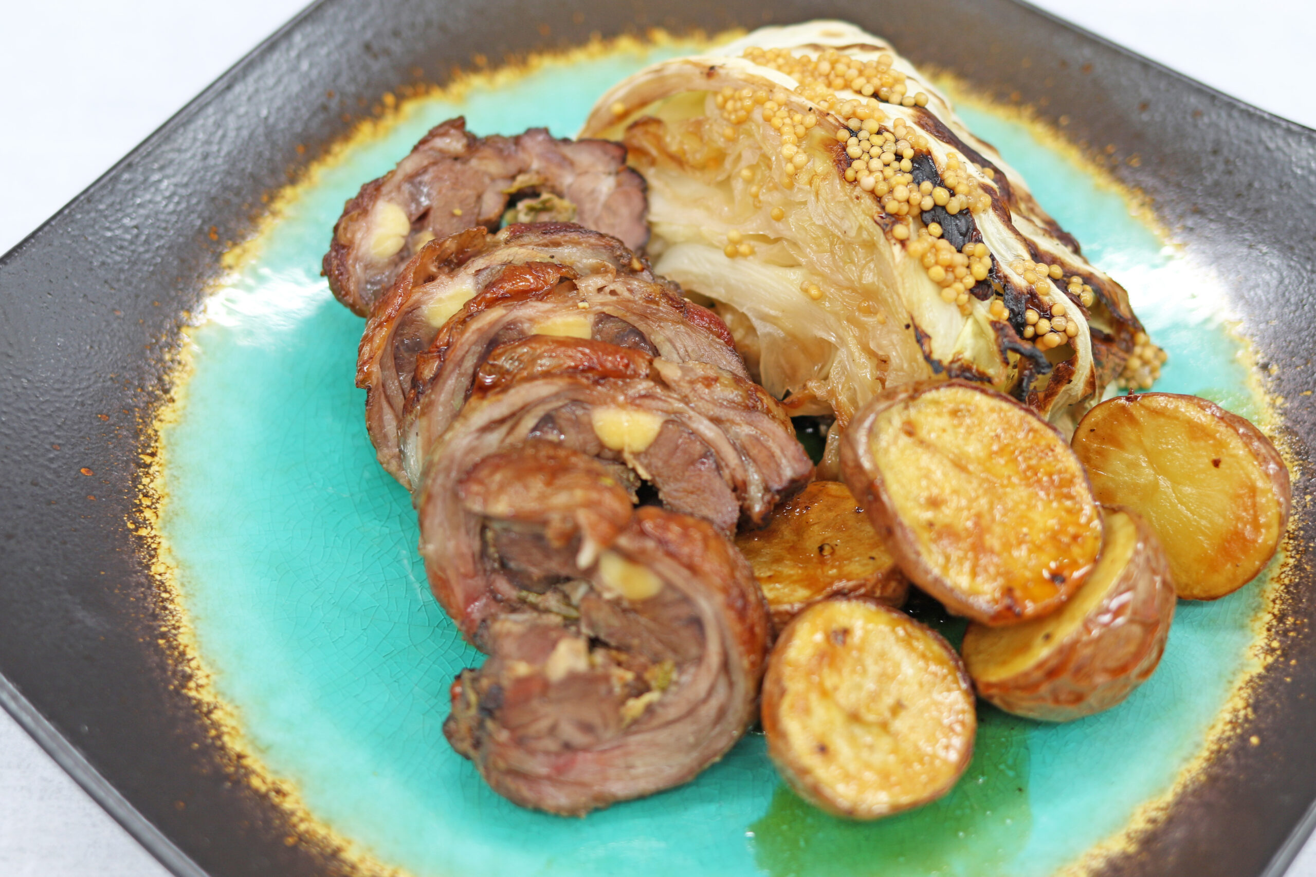 Miso-Marinated Lamb Neck with Soy-Glazed Potatoes on a brown square plate with a blue center